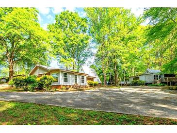 Quaint cottage-style home surrounded by lush greenery and a spacious driveway at 1098 Cown Rd, Villa Rica, GA 30180
