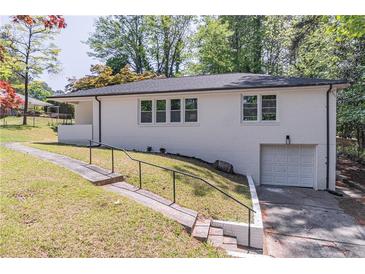 Charming white brick home with an attached garage and a landscaped front yard on a sunny day at 810 Parkway Se Dr, Smyrna, GA 30080