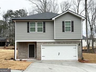 Two-story home featuring gray siding, a gray roof, black shutters, a brick facade and a two car garage at 119 Deer Xing, Temple, GA 30179