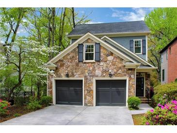 Stone front facade with a two-car garage, dark doors and shutters, and manicured landscaping at 1048 Standard Ne Dr, Brookhaven, GA 30319