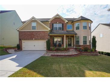 Two-story home with brick and siding exterior, well-manicured lawn, two-car garage, and decorative landscaping at 3770 Falling Leaf Ln, Cumming, GA 30041