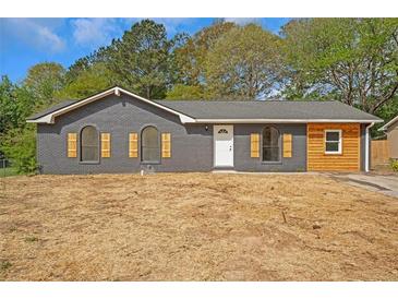 Charming grey brick home featuring arched windows and rustic wood accents at 8833 E Bourne E Dr, Jonesboro, GA 30238