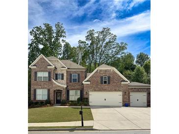 Charming brick two-story home with manicured lawn and attached two-car garage at 1710 Ashbury Park Dr, Hoschton, GA 30548