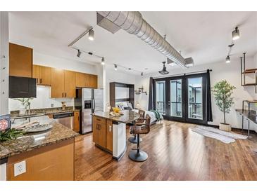 Open concept living area featuring hardwood floors, kitchen island, and balcony access at 5300 Peachtree Rd # 3601, Atlanta, GA 30341