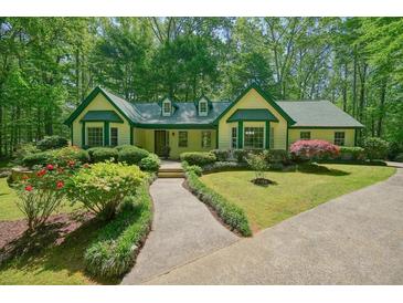 Charming home with a yellow exterior, green trim, manicured landscaping, and a welcoming walkway at 2795 Autumn Dr, Canton, GA 30115