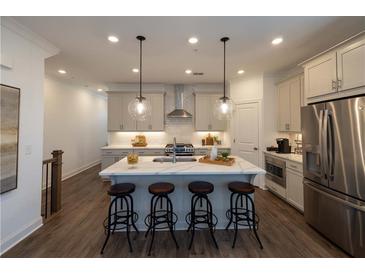Well-lit kitchen island with marble countertop, stainless steel appliances, and four bar stools at 113 Iveybrooke Ln # 61, Alpharetta, GA 30009