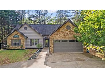Charming home featuring a stone and gray siding exterior, complemented by a well-manicured front yard and a two car garage at 130 Laguna Springs Dr, Woodstock, GA 30188