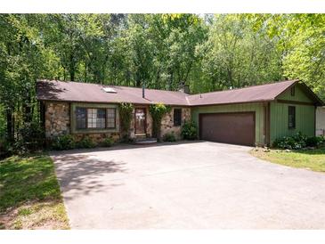 Charming stone and wood exterior with a spacious driveway and lush green trees at 247 Shallowford Nw Rd, Kennesaw, GA 30144