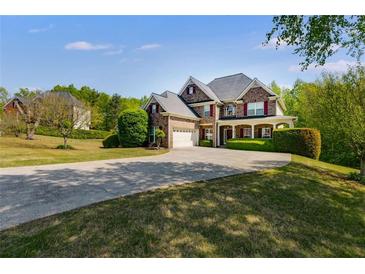 Beautiful two story brick home with red shutters and a long driveway approaching the attached two-car garage at 4828 Planters Walk, Douglasville, GA 30135