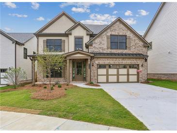 Beautiful new construction home featuring brick facade, neutral trim, tidy landscaping, and attached two car garage at 5817 Creek Indian Dr, Sugar Hill, GA 30518