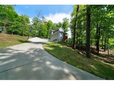 Two story home with a gray exterior, outdoor deck, and a long driveway surrounded by mature trees at 15 Swallow Se Dr, White, GA 30184