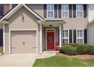 Charming home featuring a red front door, attached garage, and manicured lawn at 2557 Avery Park Cir, Atlanta, GA 30360