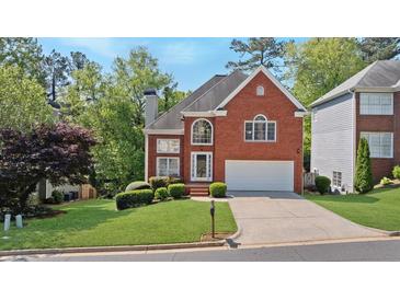 Traditional brick home with an attached two-car garage, manicured lawn, and mature trees at 370 Landing Entry, Johns Creek, GA 30022