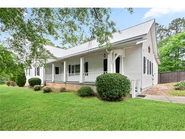 Charming two-story home boasts a white exterior, metal roof, inviting front porch, and lush green lawn at 1830 Lost Mountain Rd, Powder Springs, GA 30127