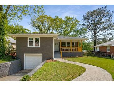 Charming brick home featuring a covered front porch, nicely landscaped lawn, and attached garage at 2358 Larchwood Sw Rd, Atlanta, GA 30310
