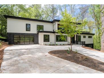 Modern home featuring a black framed glass garage door, white siding, and a curved concrete driveway at 4366 Skyland Ne Dr, Atlanta, GA 30342