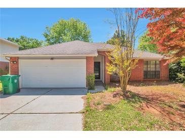 Charming one-story red brick home featuring a two-car garage, lush landscaping, and a well-maintained lawn at 814 Arbor Hill Dr, Stone Mountain, GA 30088