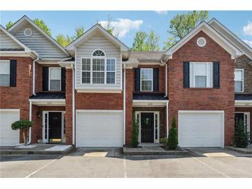 Charming brick townhouses featuring attached garages, well-kept landscaping, and inviting front doors at 215 Morris Ln, Woodstock, GA 30188