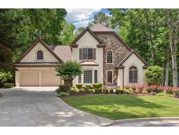 Charming home with stone accents, manicured lawn, lush landscaping, and a two-car garage at 936 Bramble Oak Ct, Powder Springs, GA 30127