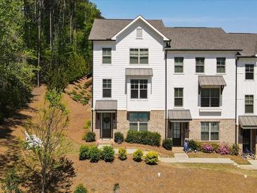 Charming townhome showcasing a blend of brick and white siding, complemented by professionally landscaped front yard at 3862 Firewood Ln # 110, Suwanee, GA 30024