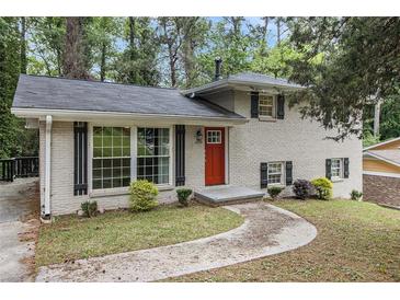 Charming home featuring a painted brick facade, complemented by a bright red front door and well-manicured landscaping at 2724 Quincy Ln, Decatur, GA 30034