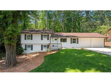 Charming split-level home featuring a manicured lawn, white siding, brown trim, and a two-car garage at 3456 Thornewood Dr, Atlanta, GA 30340