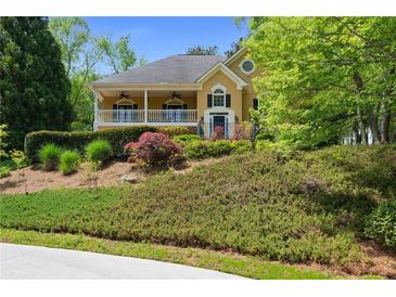 Charming yellow two-story home boasts a covered front porch and mature landscaping at 3460 Highgate Hills Ne Dr, Duluth, GA 30097