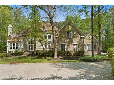 Charming stone home with manicured landscaping and a circular driveway nestled in a wooded setting at 4340 Candacraig, Johns Creek, GA 30022