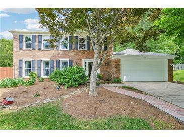 Charming two-story brick home featuring blue shutters and a well-manicured front yard with a two car garage at 725 Crab Orchard Ct, Roswell, GA 30076