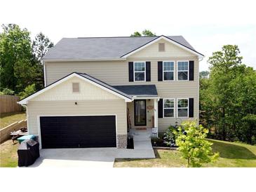 Charming two-story home with a black garage door, neutral siding, and neatly landscaped front yard at 11 Plymouth Ct, Kingston, GA 30145
