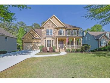 Inviting two-story home with a stone and stucco facade, a welcoming porch, and a well-manicured front yard at 823 Valley Dr, Canton, GA 30114