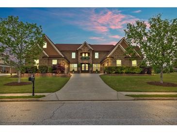 Beautiful brick home featuring a manicured lawn, lush landscaping, and an extended driveway at 401 Sara Ct, Loganville, GA 30052