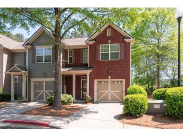 Two-story townhome featuring a brick facade, attached garage and manicured landscaping at 1396 Dolcetto Nw Trce # 12, Kennesaw, GA 30152