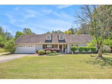 Charming single-story home with a well-manicured lawn, dormer windows, and a welcoming front porch at 65 Macadamia Ct, Covington, GA 30016
