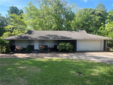Charming one-story home with a brick facade, manicured lawn, and mature trees offering curb appeal at 1379 Pair Sw Rd, Marietta, GA 30008