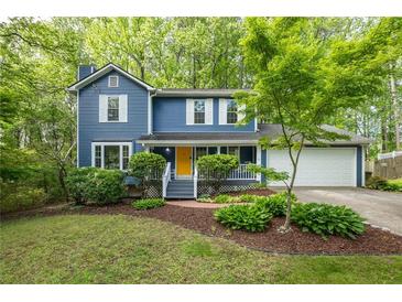 Charming blue two-story home with a yellow door, white trim, and lush landscaping at 2317 Danielle Ct, Marietta, GA 30062
