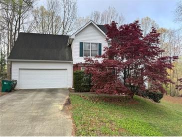 Charming two-story home with an attached garage and a well-maintained front yard with a beautiful red tree at 602 Springharbor Dr, Woodstock, GA 30188