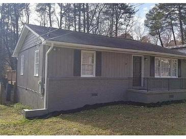 Charming single-story home featuring neutral siding, dark shutters, and a cozy front porch with black metal railing at 1677 Wayland Ne Cir, Brookhaven, GA 30319