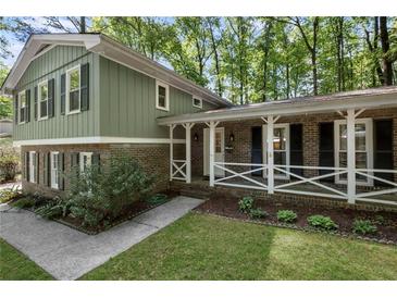 Charming two-story home featuring a brick facade, green siding, and a welcoming front porch at 4628 Mountain Creek Ne Dr, Roswell, GA 30075