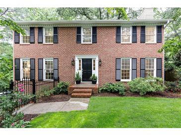 Charming brick home featuring black shutters, a manicured lawn, and lush landscaping at 535 Silver Pine Trl, Roswell, GA 30076