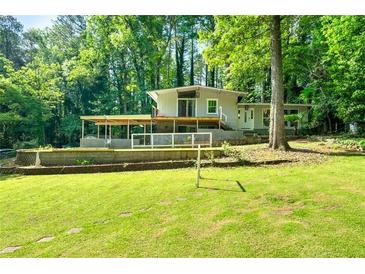 Charming home featuring a spacious front yard, covered patio, and complemented by the natural beauty of mature trees at 4882 Rock Haven Sw Dr, Lilburn, GA 30047