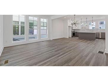 Open living room with hardwood floors, large windows, and a view of the modern kitchen at 1779 Beckham Ne Pl # 58, Atlanta, GA 30324
