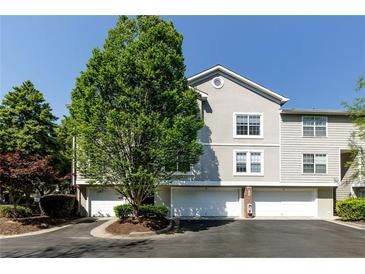 Charming townhome showcases a two-car garage and well-maintained landscaping on a bright sunny day at 4246 River Green Nw Dr # 202, Atlanta, GA 30327
