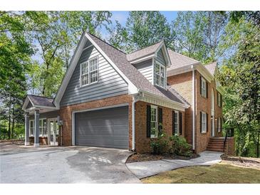 Charming brick home featuring a two-car garage, complemented by gray siding and a beautifully landscaped yard at 535 Emerald Pkwy, Sugar Hill, GA 30518