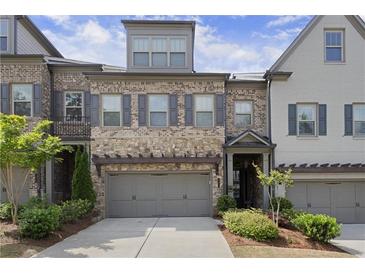 Charming townhome with a stone and brick facade, inviting curb appeal, and a two-car garage at 1074 Heyward Way, Alpharetta, GA 30009