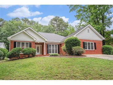 Charming brick home with a well-manicured lawn, complemented by lush greenery and flowering bushes at 1721 Druids Se Xing, Conyers, GA 30013