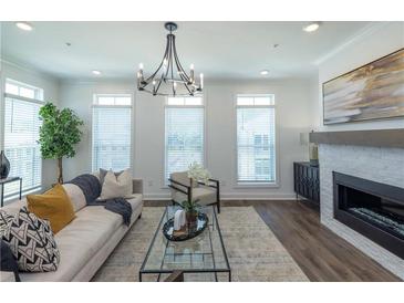 Bright living room featuring modern chandelier, fireplace, and a comfortable seating area at 114 Iveybrooke Ln # 62, Alpharetta, GA 30009