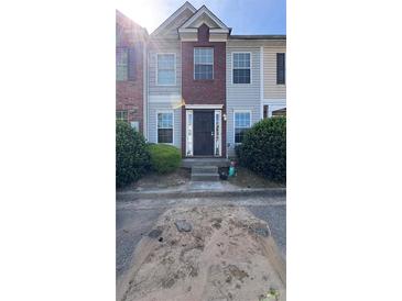 Townhouse with a red brick facade, neutral siding, and a well-maintained lawn and dark front door at 2896 Vining Ridge Ter, Decatur, GA 30034