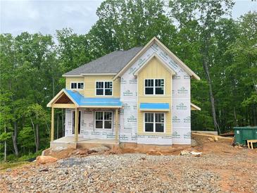 New two-story home under construction with yellow siding and a covered front porch, surrounded by lush trees at 1025 Liberty Springs Dr, Woodstock, GA 30188