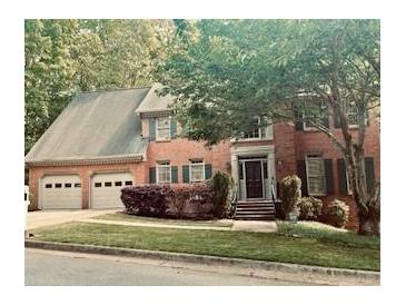 Charming brick home featuring an attached two-car garage and mature landscaping at 2355 Twelvestones Dr, Roswell, GA 30076